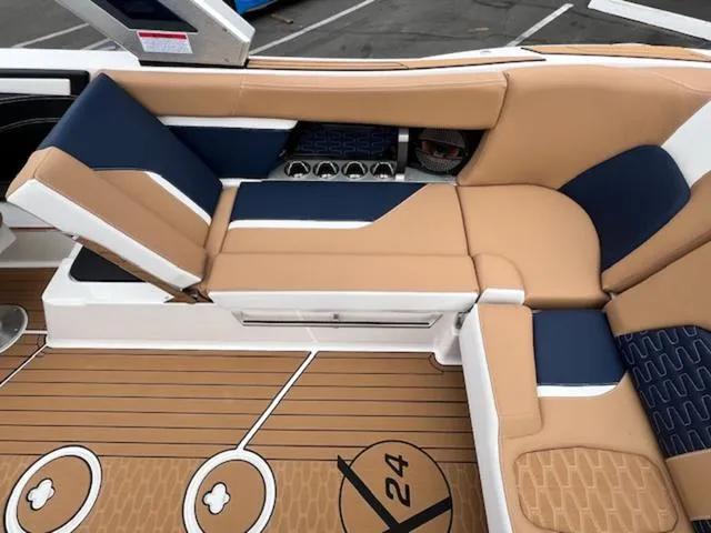Slide: The Image of 2024 MasterCraft X24 boat interior with beige and blue seating, spacious layout, and modern design. - 19