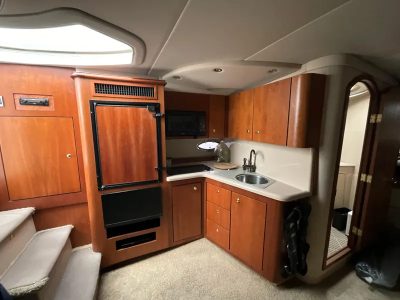 Slide: The Image of 2002 Cruisers Express boat interior kitchen with wooden cabinets and appliances. - 16