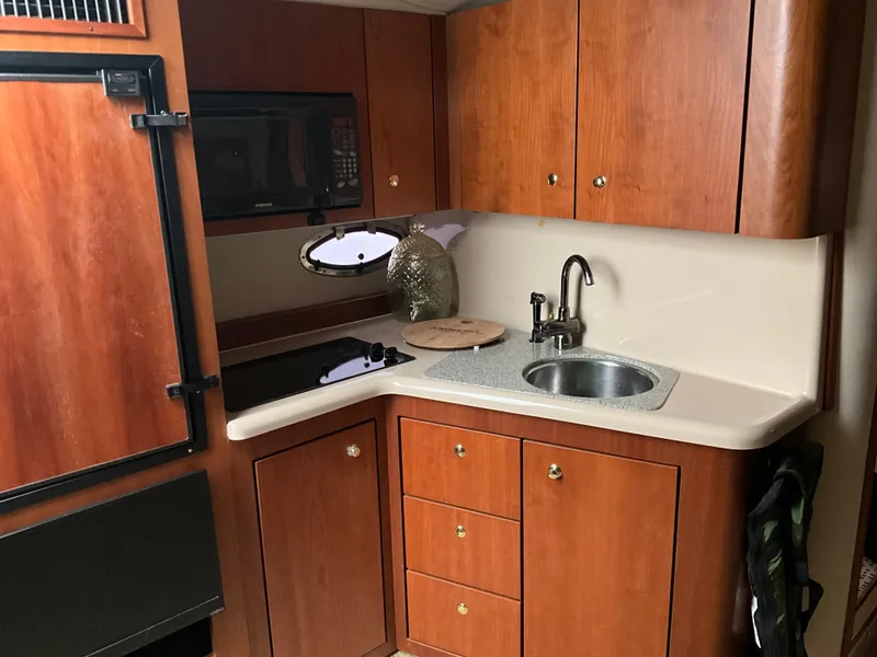 Slide: The Image of 2002 Cruisers Express boat kitchen with wooden cabinets, sink, and microwave. - 18