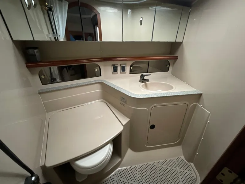 Slide: The Image of 2002 Cruisers Express boat bathroom with sink, toilet, and mirrored cabinets. - 19