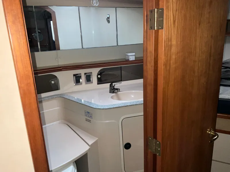 Slide: The Image of 2002 Cruisers Express boat bathroom with sink, mirror, and wooden door. - 22