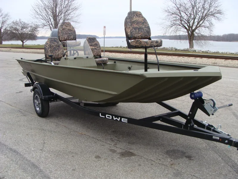 Slide: The Image of 2023 Lowe RX 1660 SC boat on trailer, camo seats, parked near lake. - 1