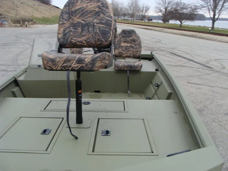 Slide: The Image of 2023 Lowe RX 1660 SC boat with camo seats, parked near a lake. - 12