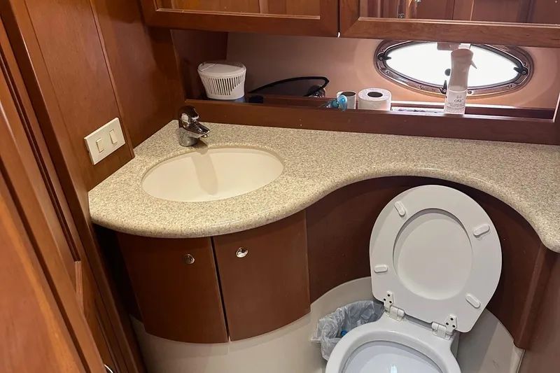 Slide: The Image of 2005 Silverton 38 Sport Bridge bathroom with sink, toilet, and porthole window. - 14