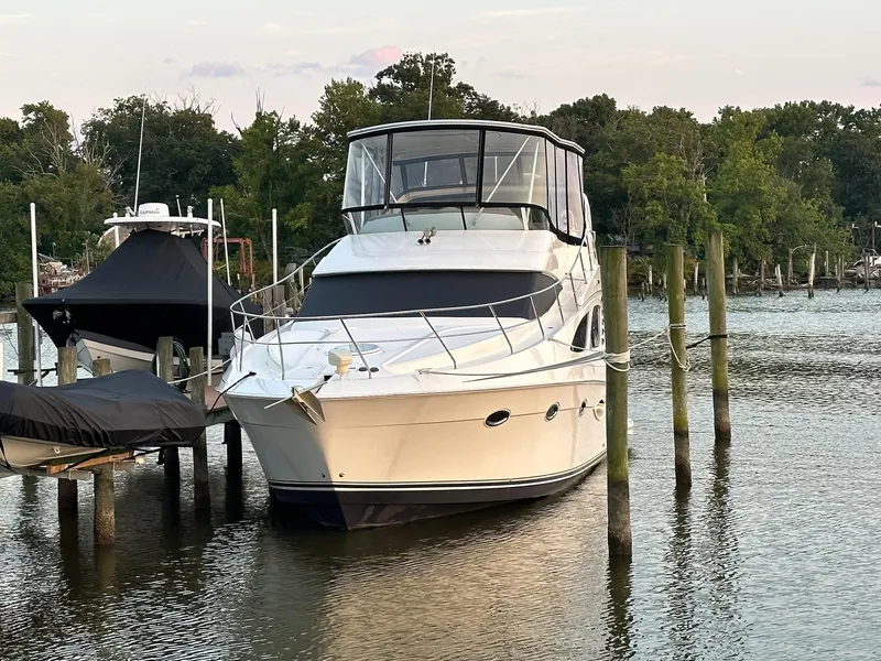 Slide: The Image of 2005 Silverton 38 Sport Bridge yacht docked on a serene lake with lush greenery. - 2
