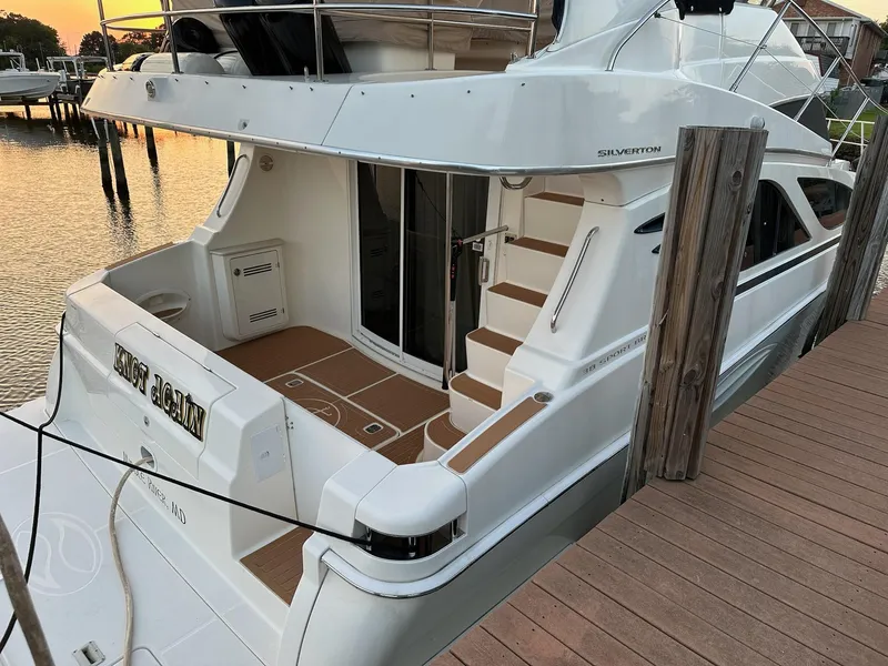 Slide: The Image of 2005 Silverton 38 Sport Bridge yacht docked at sunset, showcasing elegant design and spacious deck. - 3