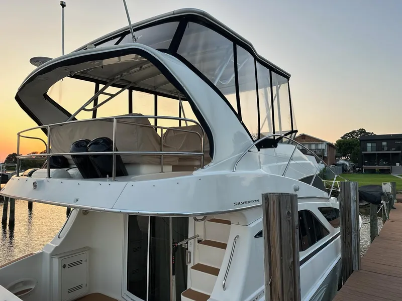 Slide: The Image of 2005 Silverton 38 Sport Bridge yacht docked at sunset, showcasing sleek design and spacious upper deck. - 4