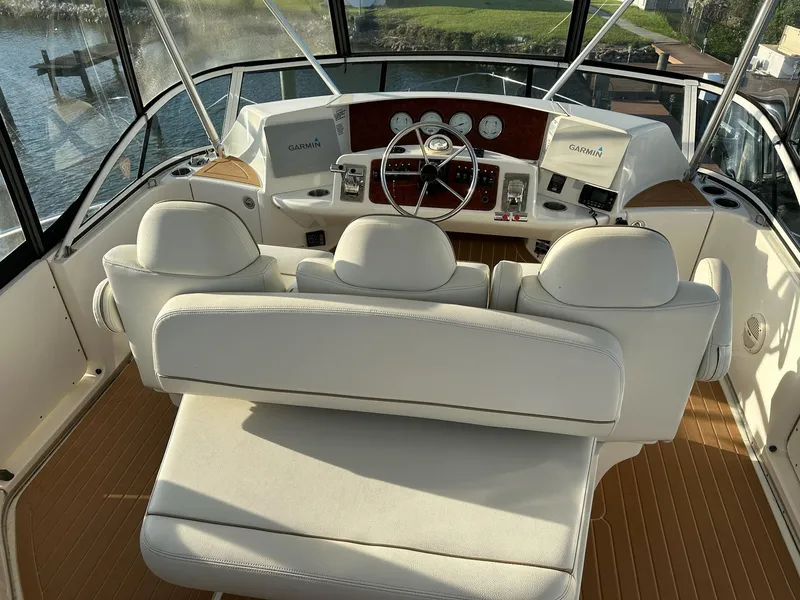 Slide: The Image of 2005 Silverton 38 Sport Bridge helm with white seating and modern dashboard controls. - 6