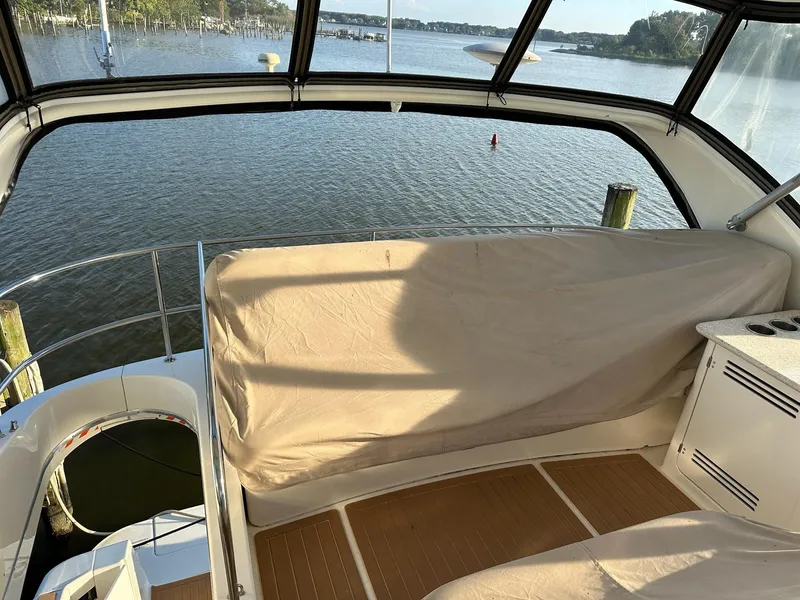 Slide: The Image of 2005 Silverton 38 Sport Bridge interior with water view, featuring covered seating area. - 8