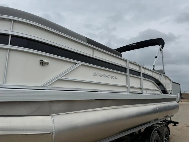 Slide: The Image of 2024 Bennington 22 S Swingback pontoon boat on trailer, overcast sky background. - 2