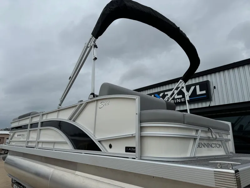 Slide: The Image of 2024 Bennington 22 S Swingback pontoon boat with canopy, displayed outdoors. - 3