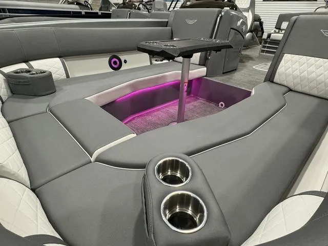 Slide: The Image of 2024 Bennington 25 LTSB boat interior with gray seating, cup holders, and ambient lighting. - 17