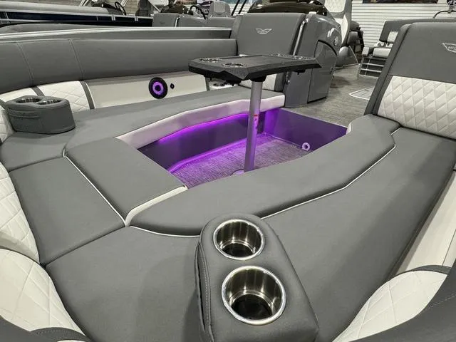 Slide: The Image of 2024 Bennington 25 LTSB boat interior with gray seating, cup holders, and purple LED lighting. - 18
