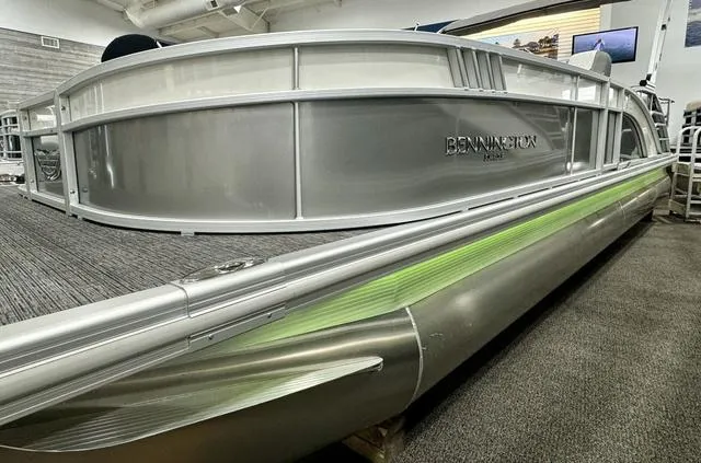 Slide: The Image of 2024 Bennington 25 LTSB pontoon boat with sleek silver design in showroom. - 2