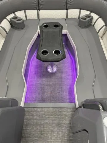 Slide: The Image of 2024 Bennington 25 LTSB boat interior with purple LED lighting and cup holders. - 8