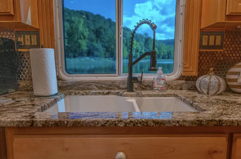 Slide: The Image of Granite kitchen sink with scenic window view, featuring modern faucet and decor. - 17