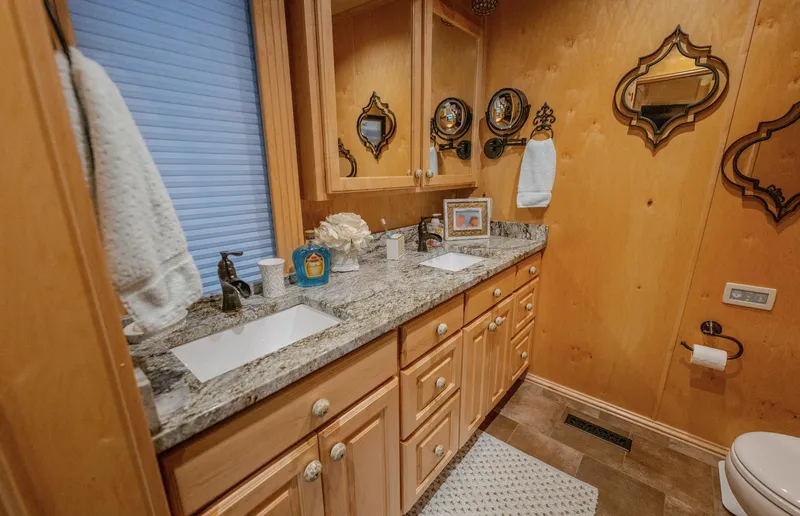 Slide: The Image of Wood-paneled bathroom with dual sinks, granite countertop, and decorative mirrors. - 19