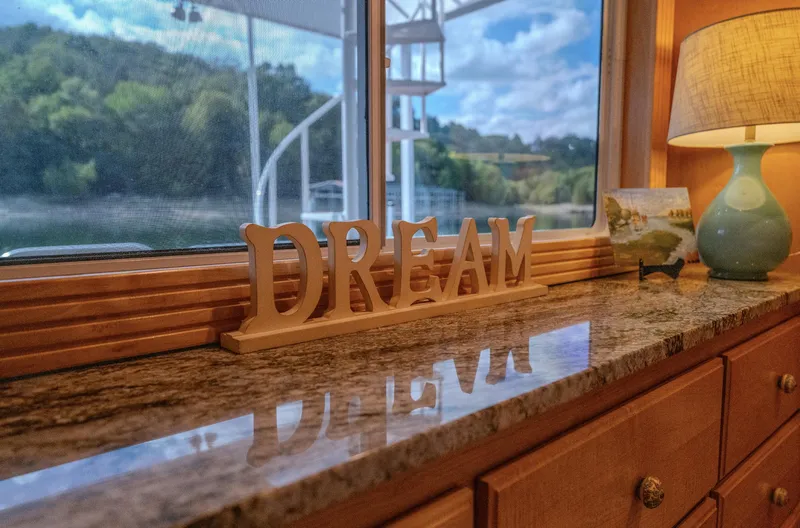 Slide: The Image of Decorative "DREAM" sign on a houseboat's granite counter, with scenic window view. - 22