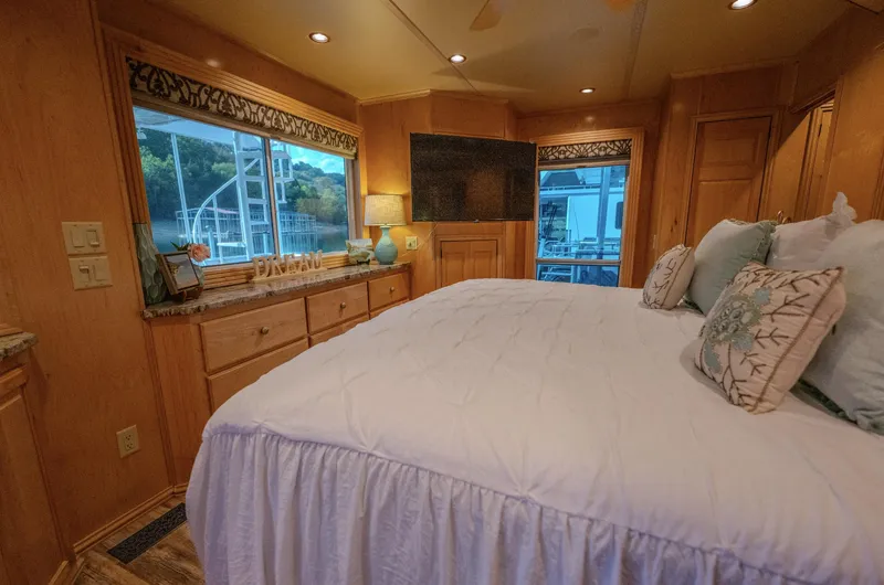 Slide: The Image of Luxurious bedroom interior in a 2007 Fantasy houseboat, featuring a large bed and scenic window view. - 23