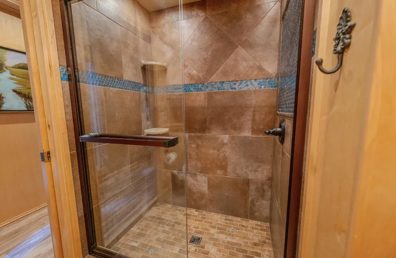 Slide: The Image of Luxurious tiled shower with glass door, featuring brown and blue accents, modern design. - 25