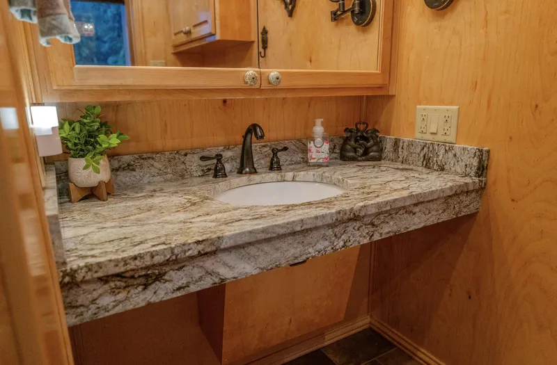 Slide: The Image of Rustic bathroom with granite countertop, wooden walls, and modern fixtures. - 26