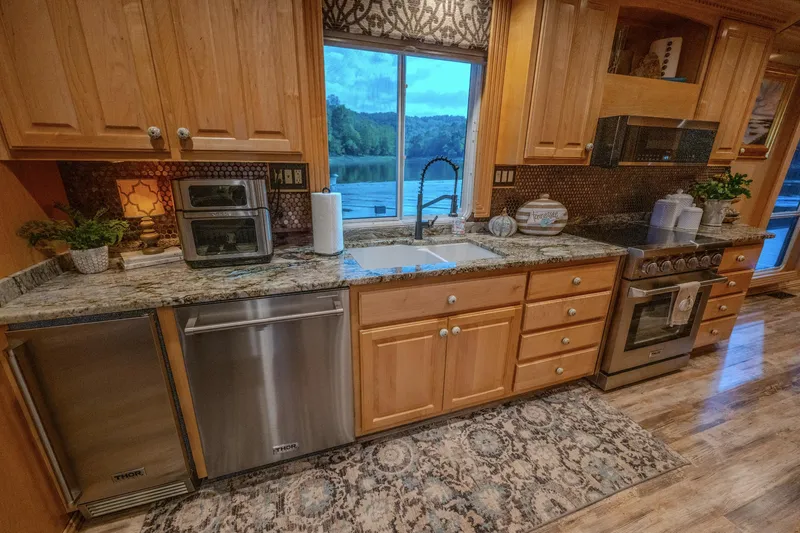 Slide: The Image of Modern kitchen with wooden cabinets, granite countertops, and stainless steel appliances, overlooking scenic view. - 34
