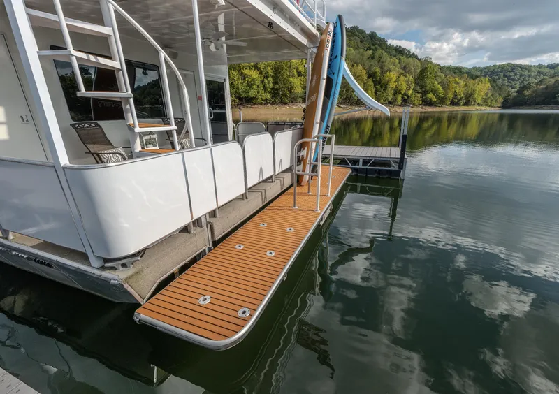 Slide: The Image of Houseboat with slide on calm lake, surrounded by lush green trees. - 4