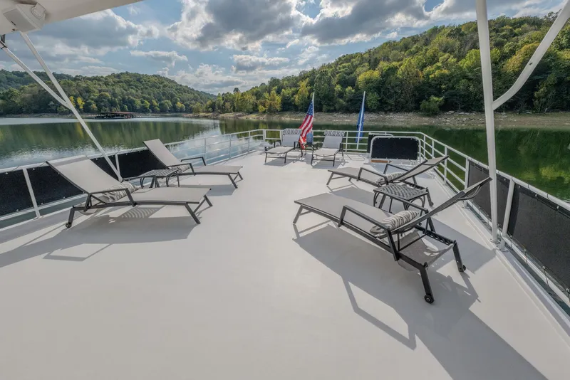 Slide: The Image of Spacious deck of 2007 Fantasy 19 X 90 houseboat with lounge chairs, lake view, and flags. - 7