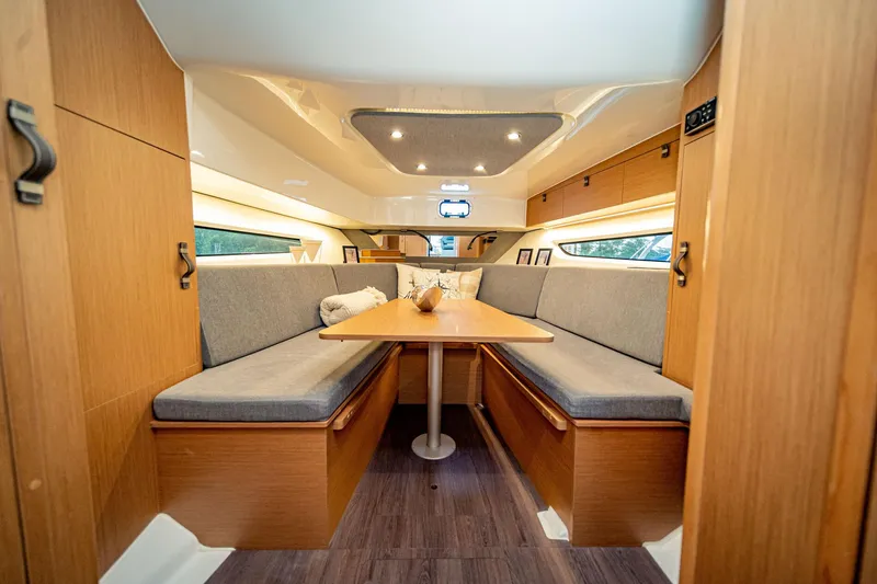 Slide: The Image of 2024 Beneteau Flyer 10 cabin interior with cozy seating and wooden table. - 12