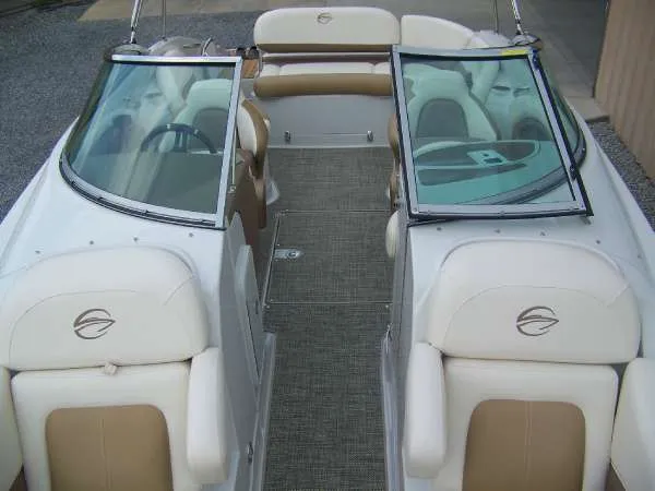 Slide: The Image of 2016 Crownline E4 boat interior with beige and white seating, dual windshields, and carpeted flooring. - 14