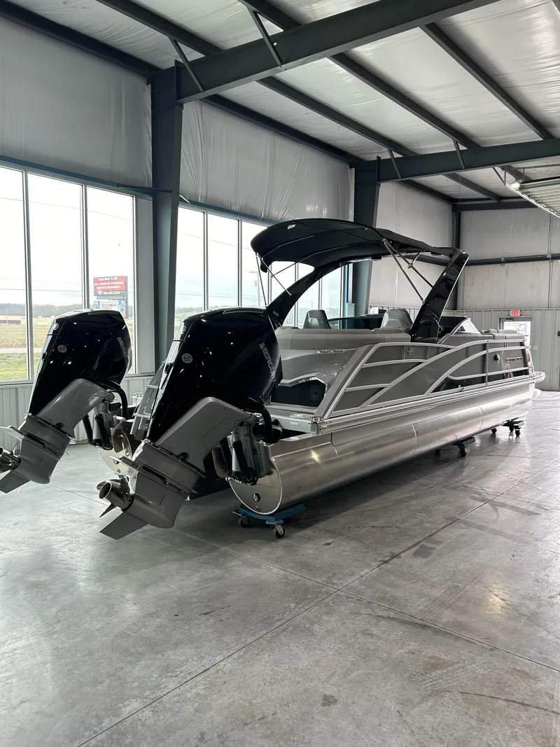 Slide: The Image of 2024 Bennington 27 QFBA pontoon boat with dual outboard motors in a showroom. - 3