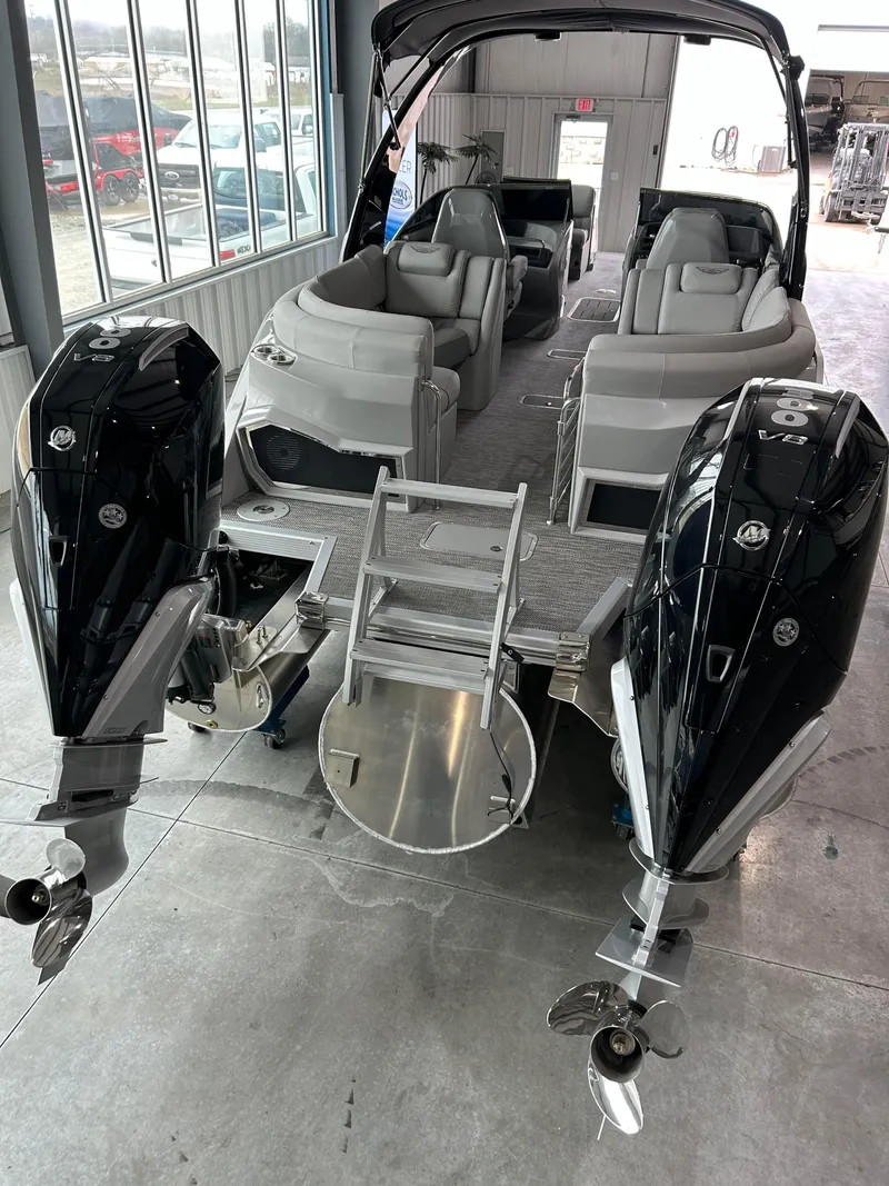 Slide: The Image of 2024 Bennington 27 QFBA pontoon boat with dual outboard motors in a showroom. - 4