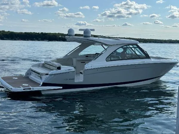 Slide: The Image of 2023 Regal LS36 boat on a calm lake under a partly cloudy sky. - 1