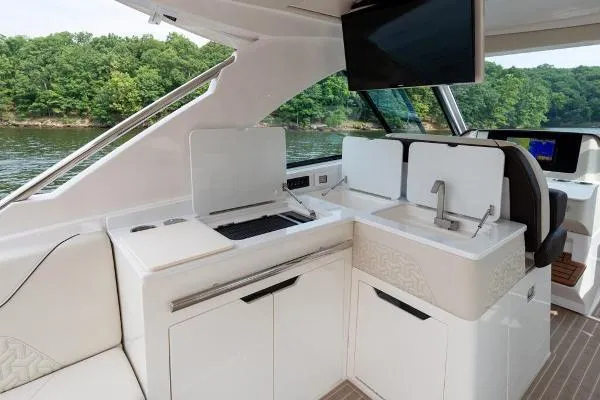 Slide: The Image of 2023 Regal LS36 yacht interior with kitchenette, sink, and TV, overlooking a scenic water view. - 7