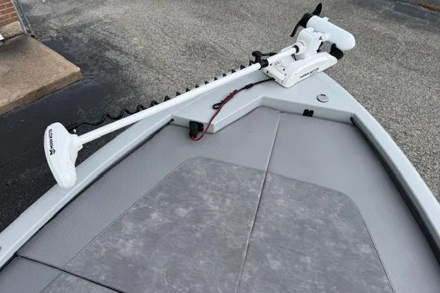 Slide: The Image of 2024 Avid 23 Fusion boat with trolling motor on deck, gray surface, outdoor setting. - 11