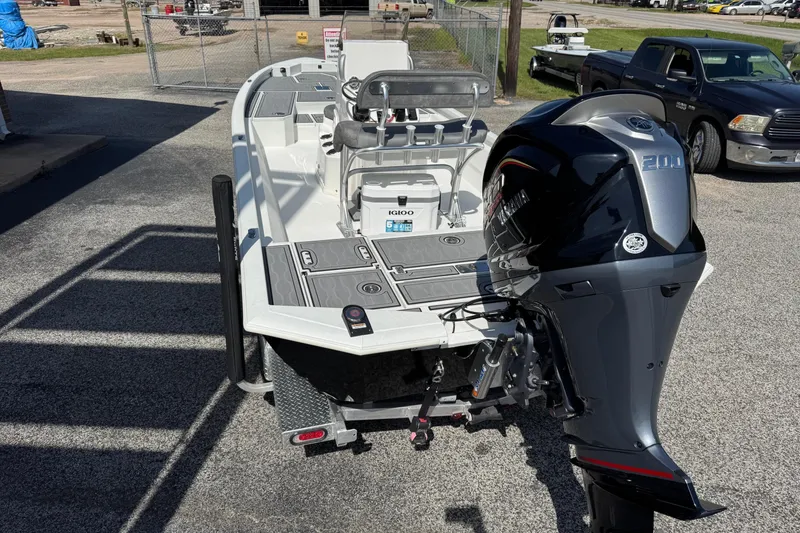 Slide: The Image of 2024 Avid 23 Mag boat with powerful outboard motor, parked on pavement. - 2