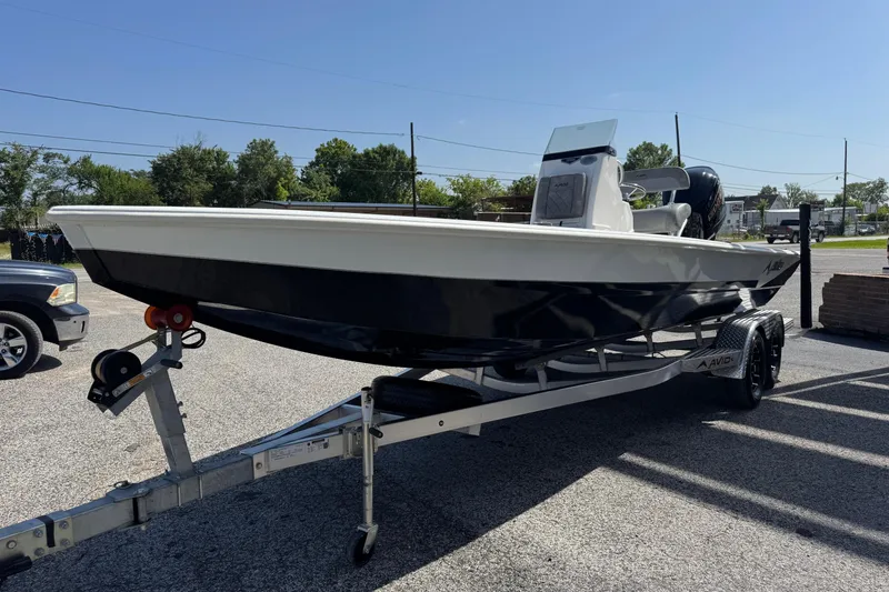Slide: The Image of 2024 Avid 23 Mag boat on trailer, parked outdoors under clear sky. - 6