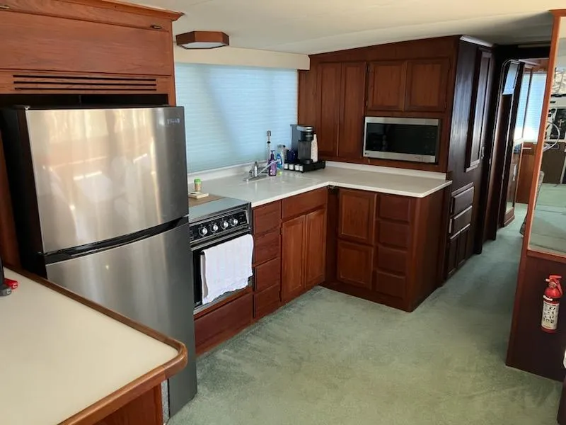 Slide: The Image of 1989 Bluewater Yachts 55' Coastal Cruiser kitchen with modern appliances and wooden cabinetry. - 14