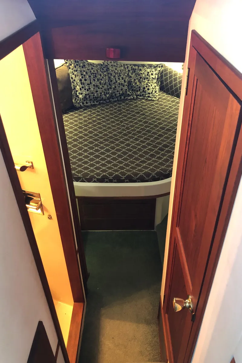 Slide: The Image of 1989 Bluewater Yachts 55' Coastal Cruiser bedroom with cozy bed and wooden doors. - 41