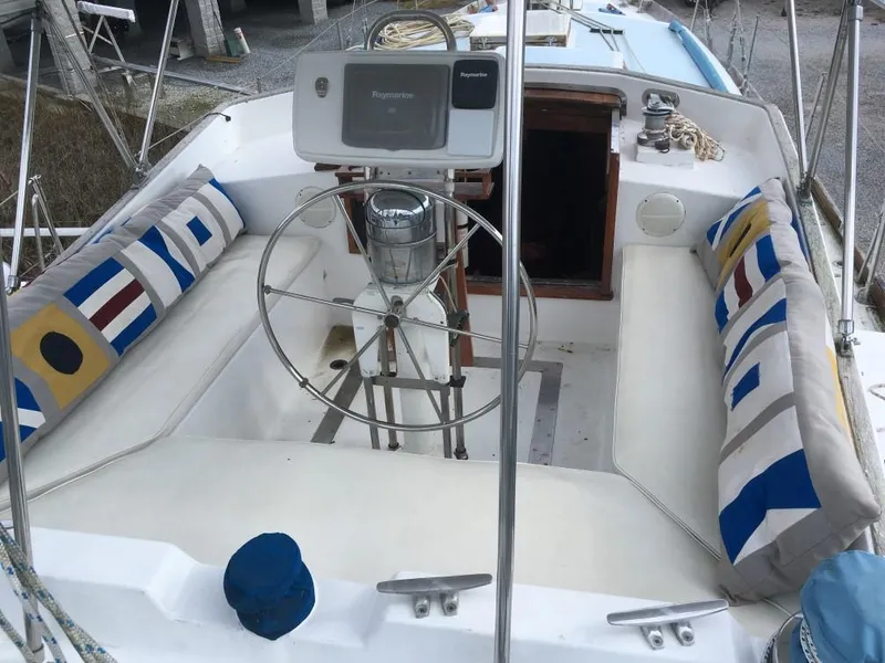 The Image of 1973 Hodgdon DOLPHIN 47 sailboat cockpit with nautical-themed cushions and steering wheel. - 0