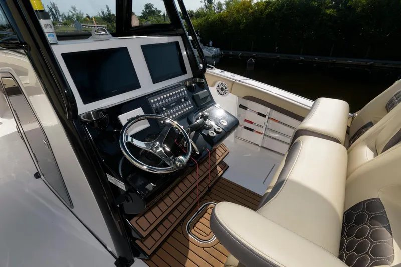 Slide: The Image of 2023 Tidewater 320 CC Adventure boat helm with dual screens and leather seating. - 11
