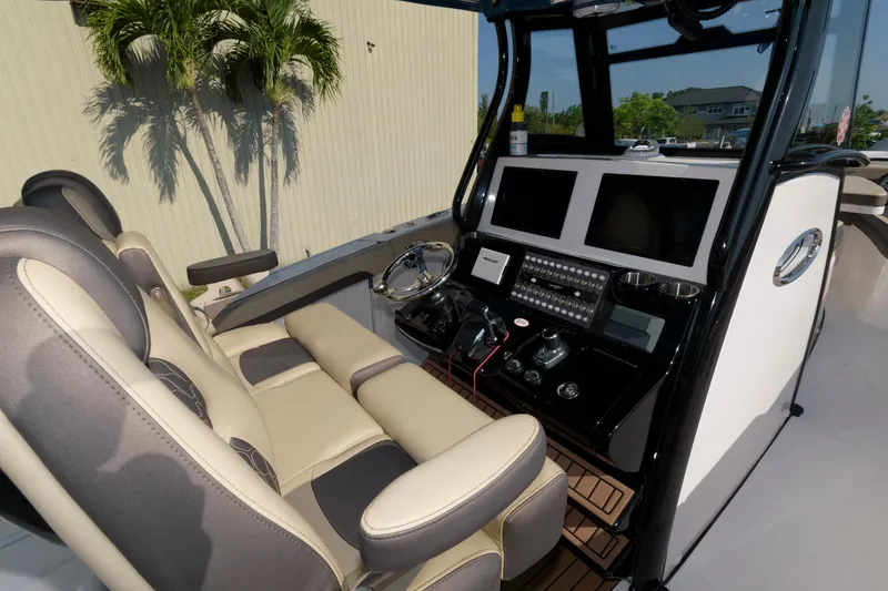 Slide: The Image of 2023 Tidewater 320 CC Adventure boat cockpit with dual screens and comfortable seating. - 13