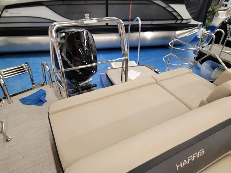 Slide: The Image of 2024 Harris Cruiser 250 pontoon boat with beige seating and outboard motor. - 16