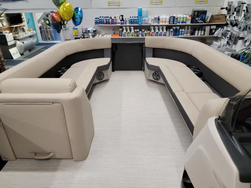 Slide: The Image of 2024 Harris Cruiser 250 boat interior with beige seating in a showroom. - 22
