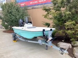 Slide: The Image of 2024 Mako Pro Skiff 13 CC on trailer, parked outdoors near trees. - 1