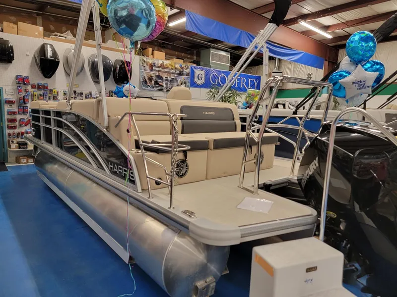 Slide: The Image of 2024 Harris Cruiser 210 pontoon boat on display in showroom with balloons. - 4