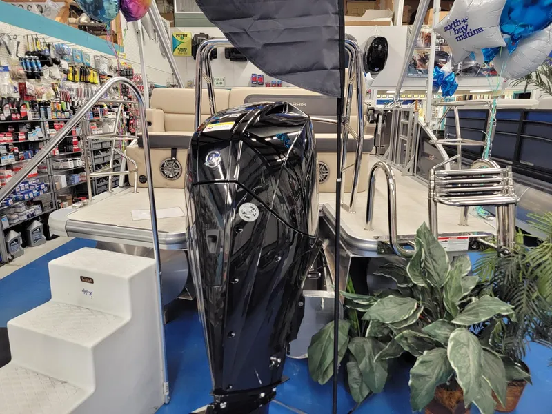 Slide: The Image of 2024 Harris Cruiser 210 boat displayed in a showroom with a black outboard motor. - 5