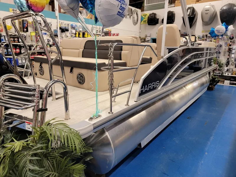 Slide: The Image of 2024 Harris Cruiser 210 pontoon boat on display in a showroom. - 6