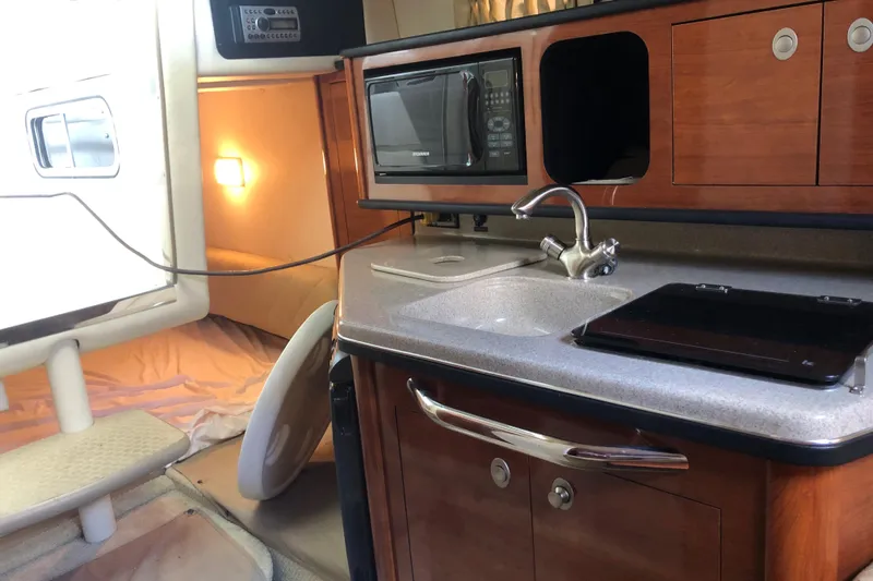 Slide: The Image of Interior of 2007 Sea Ray 260 Sundancer with kitchenette, sink, microwave, and wooden cabinetry. - 30