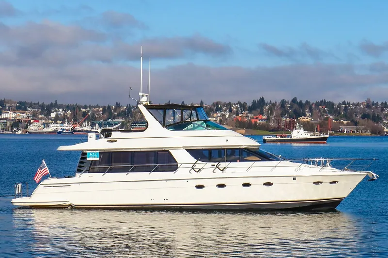 The Image of 2005 Carver 560 Voyager yacht on calm water with cityscape background. - 1